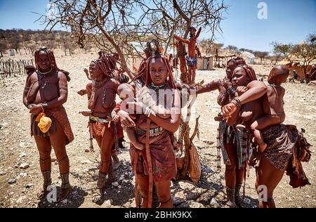 A group of colourful Himba women with kids in their village in Kaokoveld. Stock Photo