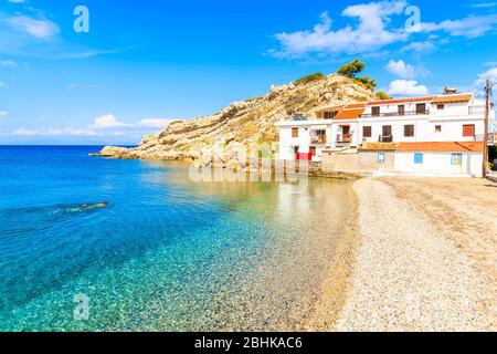 Snorkeler swimming in crystal clear azure sea water in Kokkari village with typical white houses on shore, Samos island, Aegean Sea, Greece Stock Photo