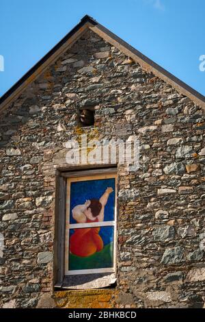 Colorful decorated painted window of residential stone building wall depicting woman after waking up in Killarney, Ireland Stock Photo