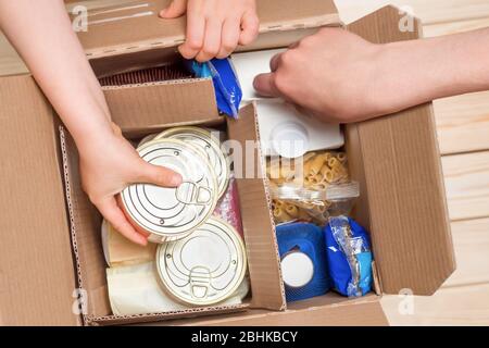 Assistance concept at quarantine time because of coronavirus infection Covid-19. Hands opening a food delivery box at home, online ordering. Grocery Stock Photo