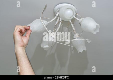 man changes a light bulb in a lighting device. man or husband for an hour Stock Photo