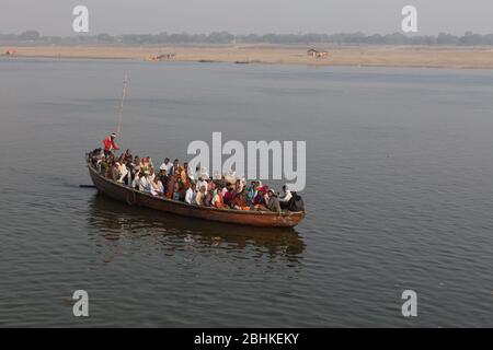 A big group of people taking a ride in a boat in the evening to see the view of ghats on the bank of river Ganges Stock Photo