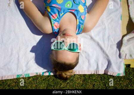 Young girl sunbathing with green sunglasses on Stock Photo