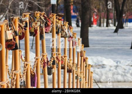 Wedding locks on the railing of the bridge in the park in winter Stock Photo