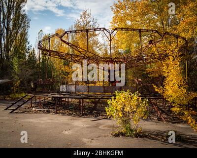 Abandoned amusement park in ghost town Pripyat. Overgrown trees and collapsing buildings in Pripyat, Chernobyl exclusion zone. Ukraine Stock Photo