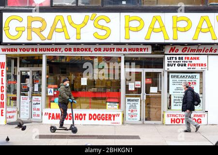 People wearing masks pass by a closed Gray's Papaya in the Upper West Side in the time of coronavirus COVID-19, New York, NY, 23rd April 2020. Stock Photo