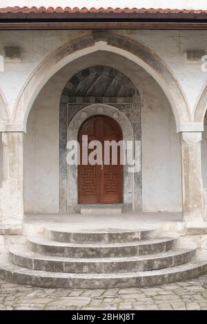 Entrance to an old Muslim building in oriental style, through an arch with columns, steps, carved doors. in front of cable tiles Stock Photo