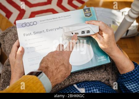 Paris, France - Circa 2020: Young explaining to senior male during unboxing unpacking new parcel from Amazon Prime containing latest TP-Link Deco M9 Plus AC2200 Smart Home Mesh Wi-Fi System Stock Photo
