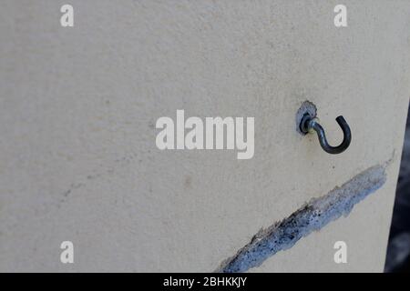 rusty hook on a painted garden wall Stock Photo