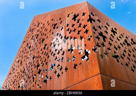 A building with raw metal walls covered with rust, cut out shapes of crosses. Stock Photo