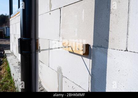 A black metal gutter attached to the raw wall of the house to make a distance to insulate the building. Stock Photo