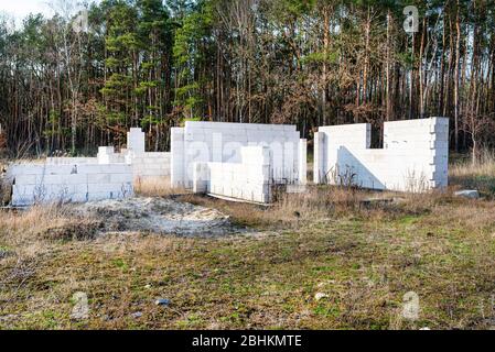 Abandoned house construction, load-bearing walls made of cellular concrete, visible reinforcement bars. Stock Photo