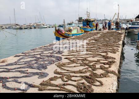 Fishing nets laid out to dry on the quayside, Marsaxlokk, Malta Stock Photo