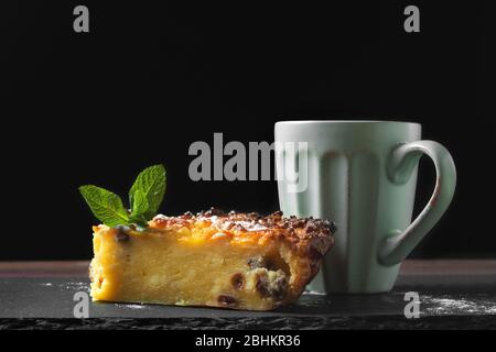 Cottage cheese casserole with mint leaves and a cup of coffee or tea. Pie with black background Stock Photo