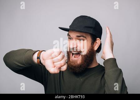 Young bearded man is stressed when he sees the time on his wrist watch. Stock Photo