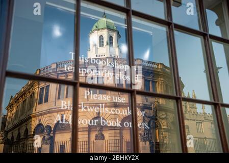 The Sheldonian Theatre, Oxford, is reflected in the window of Blackwell's bookshop, closed during the Covid-19 pandemic of April 2020 Stock Photo