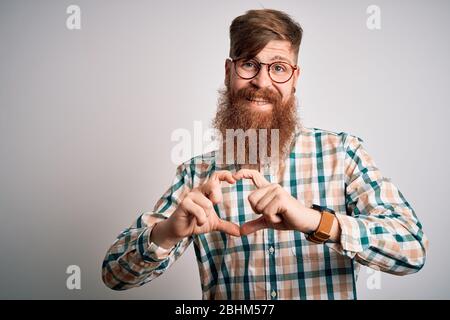 Handsome Irish redhead man with beard wearing glasses and hipster shirt smiling in love showing heart symbol and shape with hands. Romantic concept. Stock Photo