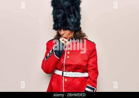 Middle age beautiful wales guard woman wearing traditional uniform over white background feeling unwell and coughing as symptom for cold or bronchitis Stock Photo