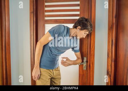 Man wearing mask opening the door with the elbow for protection infection COVID-19 Stock Photo