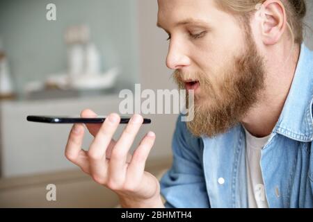 Young man using virtual digital voice assistant on mobile phone, closeup. Stock Photo