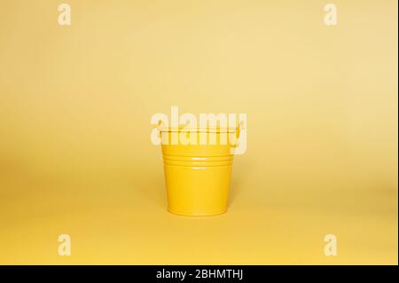 Empty yellow metal miniature bucket on a clean yellow flat background Stock Photo