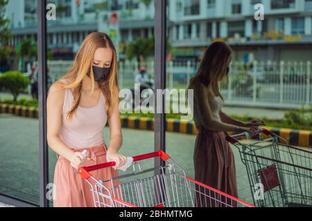 Woan hand disinfecting shopping cart with alcohol spray for corona virus or Covid-19 protection Stock Photo