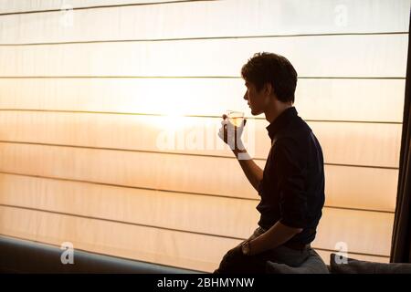 Young Chinese businessman drinking alcohol in hotel room Stock Photo