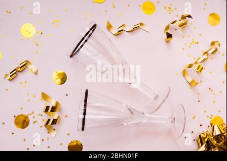 quality two empty clean glasses for drinks on a clear delicate beige background with a golden foil bow, ribbon, yellow circles and gold spirals serpen Stock Photo