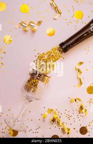 shiny gold stars fall out from a beautiful bottle of dark glass to glass with a gold border on a delicate beige background with yellow circles and gol Stock Photo