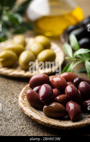 Variety of black and green olives and olive oil in bowls on stone background close up Stock Photo