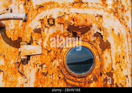 the door and porthole of a very old abandoned completely rusty ship Stock Photo