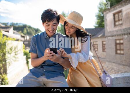 Happy young Chinese couple using smartphone outdoors Stock Photo