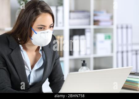 Executive woman wearing protective mask working reading on laptop at the office Stock Photo