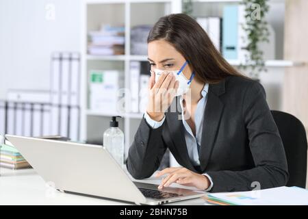 Executive exposing herself to contagion touching protective mask working at office Stock Photo