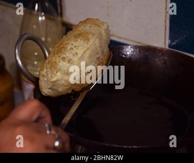 Deep Frying Hot Bengali Luchi taken our from pan called Karhai. It is traditional bengali dish, food or cuisine. Luchi or poori are deep fried bread Stock Photo