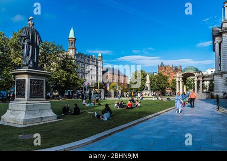 Park with many people lying on the meadows in front of City Hall in Belfast, United Kingdom. Belfast is the capital of northern Ireland. Stock Photo