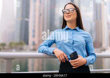 portrait of a young attractive blond woman talk by mobile phone with inspiration, big city skyscrapers on background Stock Photo