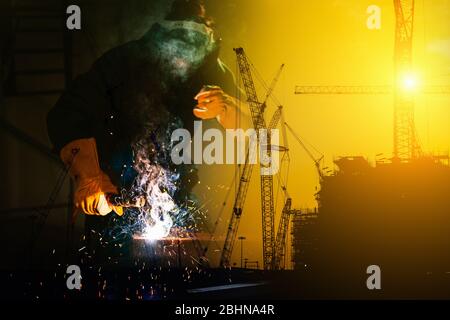 Double Exposure of Craftsman Welder is Welding Steel Frame on Construction Site Background, Welder Man in Safety Protective Equipment Doing Structure Stock Photo