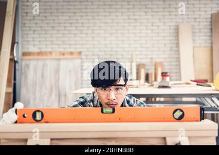 Carpenter Man is Working Timber Woodworking in Carpentry Shop, Craftsman is Leveling Alignment Timber Plank for Wooden Furniture in Workshop. Workmans Stock Photo