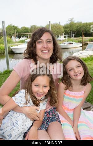 Portrait Of Happy modern Family In Garden with single mother and two sisters daughters Stock Photo