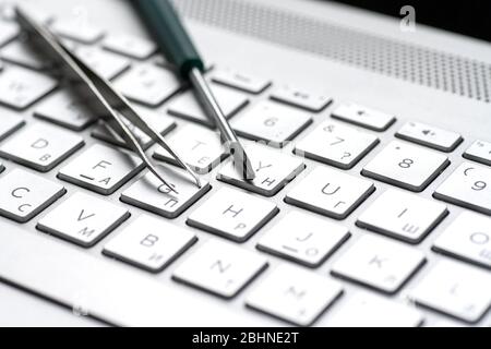 Laptop repair, screwdrivers close-up on a gray keyboard. Computer service macro Stock Photo