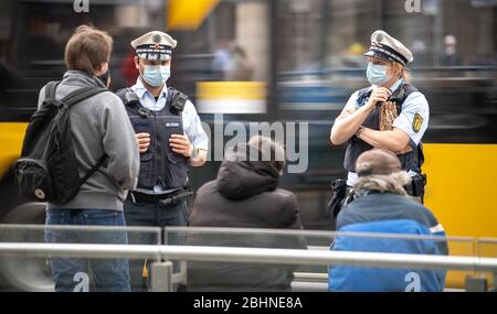 Stuttgart, Germany. 27th Apr, 2020. Police officers approach three men at a stop of the Stuttgart trams (SSB). In order to slow down the spread of the corona virus, masks are compulsory in public transport and shopping in almost all German states. Credit: Sebastian Gollnow/dpa/Alamy Live News