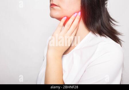 The girl clings to the inflamed salivary gland in which pain. Concept of salivary gland disease, mumps, cancer, copy space, retention cyst Stock Photo