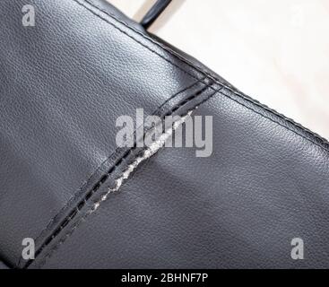 Torn and battered leather on a black office computer chair. Restoration and restoration of the leather Stock Photo