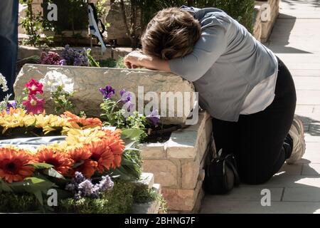 Jerusalem, Israel. 27th Apr, 2020. Rebecca mourns her brother Yehuda Ben Arush, killed in Bethlehem in 1997 while in IDF reserve duty, 35, married and the father of two. Families visit the graves of the fallen at the Mt. Herzl Military Cemetery ahead of Memorial Day, to be commemorated 28th April, 2020. Military Cemeteries will close today at 14:00 as government will impose a total lockdown nationwide on Memorial Day and the following Independence Day in an attempt to further curb COVID-19 spread. Credit: Nir Alon/Alamy Live News