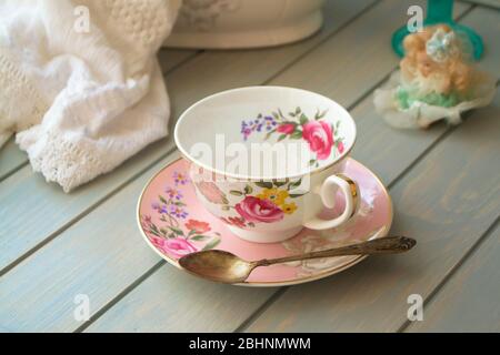 Pink vintage porcelain tea cup on turquoise table. Stock Photo