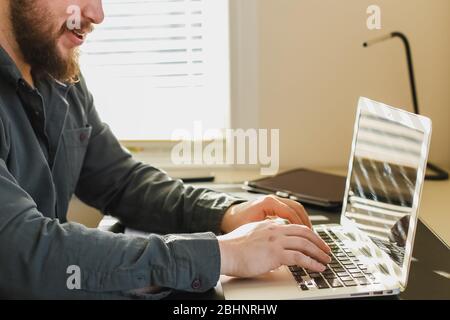 Bearded man chatting in social networks by laptop at office. Stock Photo