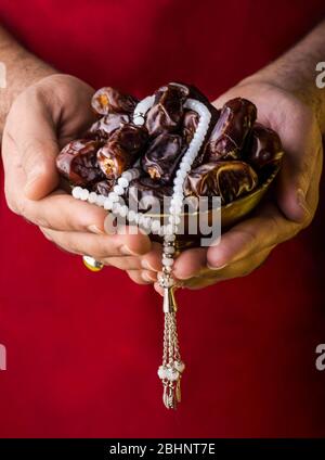 Iftar Image Hands holding a bowl of dates with Tasbeeh Ramadan Mubarak concept, fasting and Iftar fruits background Stock Photo