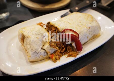 Chicken burrito ,Mexican and Tex-Mex cuisine consists of a flour tortilla with various other ingredients wrapped into a closed-ended cylinder shaped Stock Photo