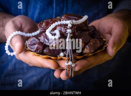 Young men Hands holding a bowl of dates with tasbeeh ramadan mubarak concept, fasting and iftar fruits background Stock Photo